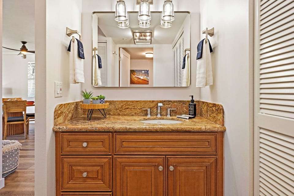 The bathroom at Mahana 1118 boasts granite counters, rich wood cabinetry, and modern fixtures.