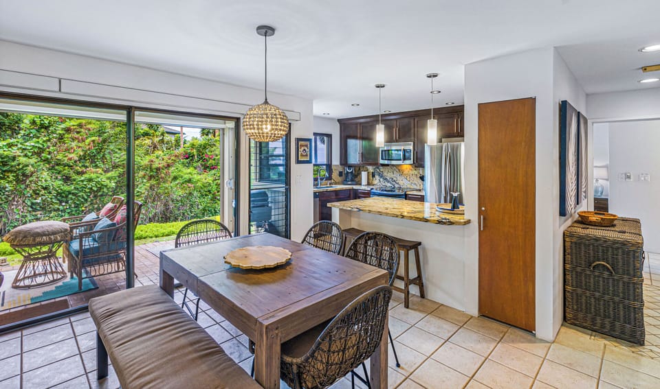 The open-concept dining area and kitchen at Wailea Ekolu 1605 seamlessly connect to the lanai and garden views.