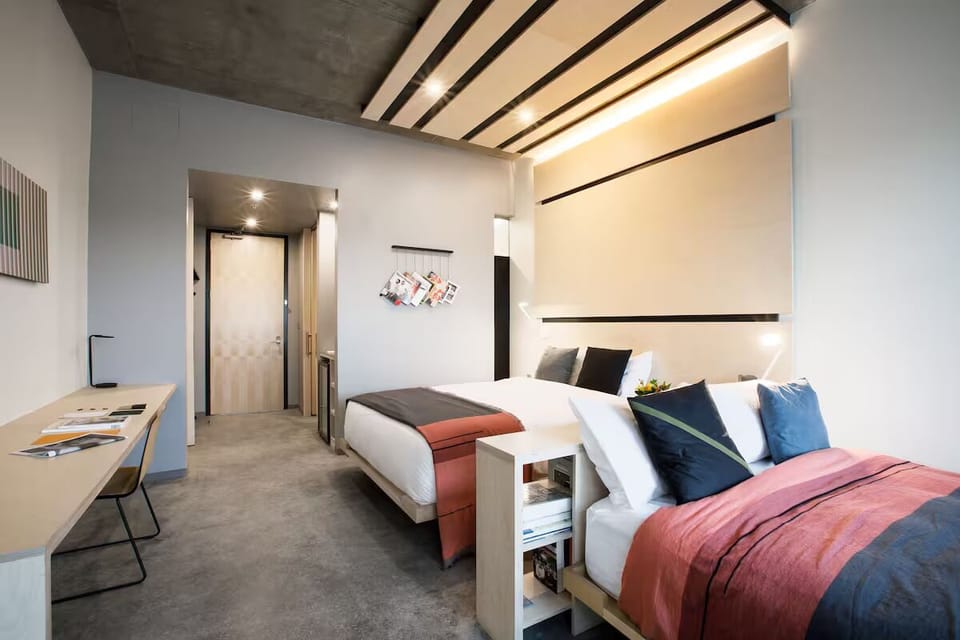 Settle into crisp linens beneath modern lighting and calm tones.