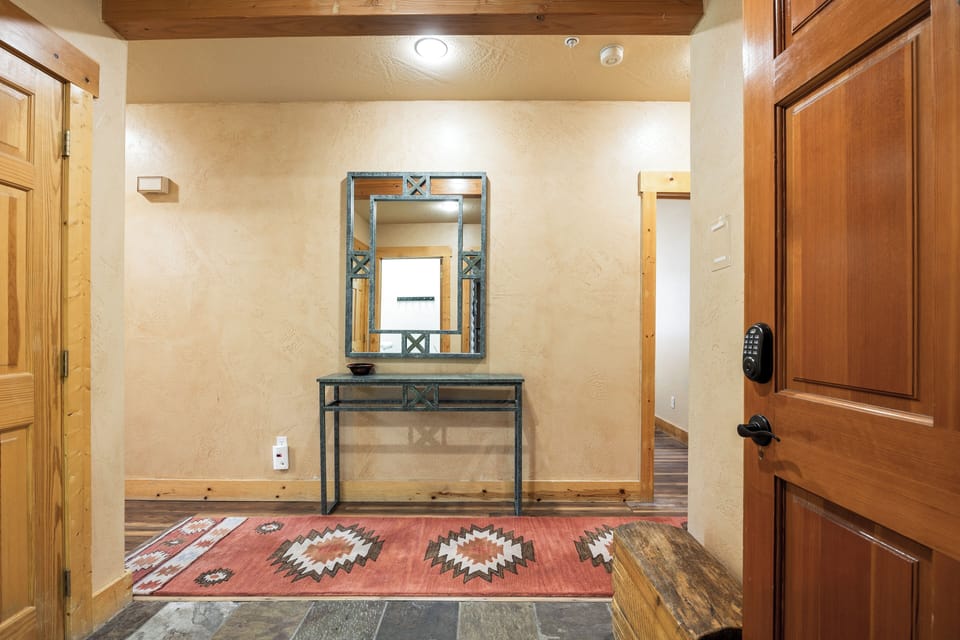 - Welcoming entryway with rustic console and mirror  
- Southwestern rug adds mountain lodge character  
- Bright lighting and warm wood finishes greet you