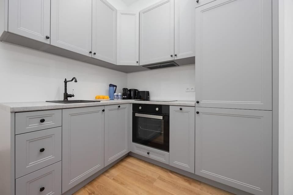 A compact kitchen with modern gray cabinetry, a built-in oven, and wooden countertops, offering both style and functionality in a small space.
