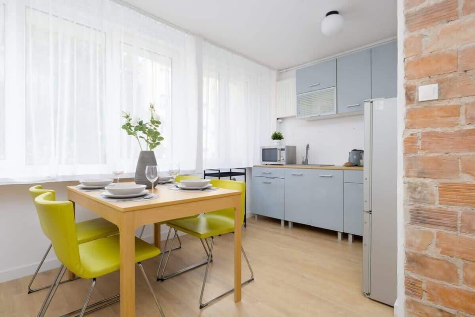 A dining corner with a bright yellow table setup near a white kitchen.


