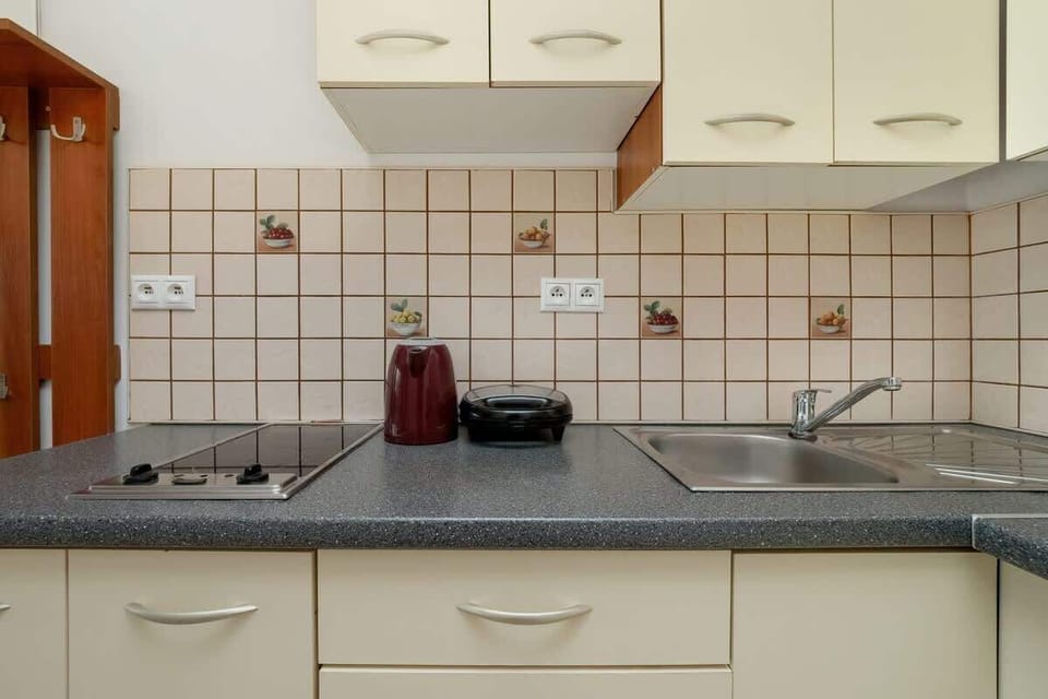 A second kitchen with beige cabinetry, tiled backsplash, and a compact countertop.

