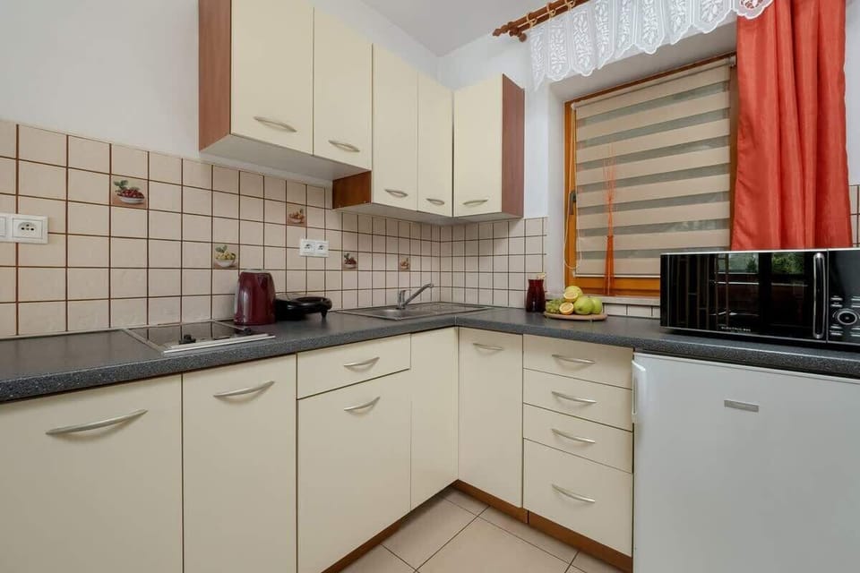 A functional kitchen with white cabinets, red accents, and a built-in oven.

