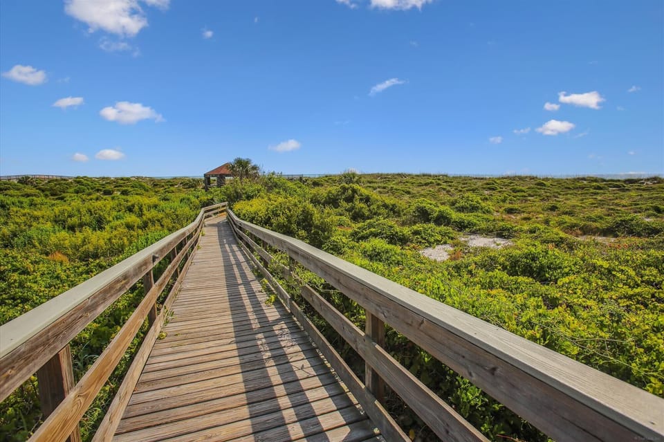 - Scenic boardwalk path through lush greenery leading to the beach  
- Elevated walkway ensures easy and direct access to the shoreline  
- Enjoy a peaceful stroll surrounded by natural coastal beauty  