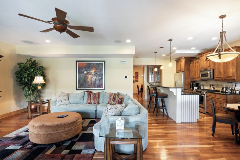 - Open-concept design connecting living room and kitchen  
- Large sectional sofa perfect for family movie nights  
- Pendant lights highlight breakfast bar and wood finishes