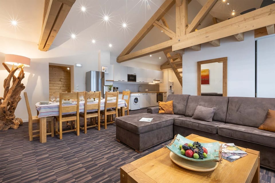This open-plan living room features plush seating, high wooden ceilings, and rustic decor, creating a cozy and welcoming atmosphere for relaxing or socializing with family and friends.