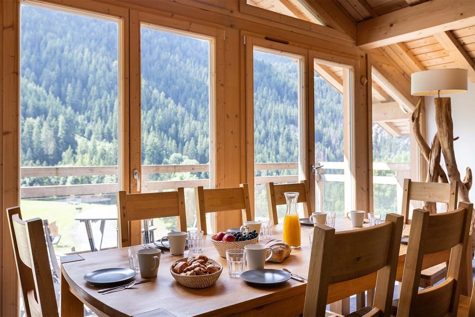 This bright dining space features floor-to-ceiling windows, allowing you to enjoy panoramic mountain views while sharing a meal. The wooden table and warm decor create a cozy atmosphere for family gatherings.