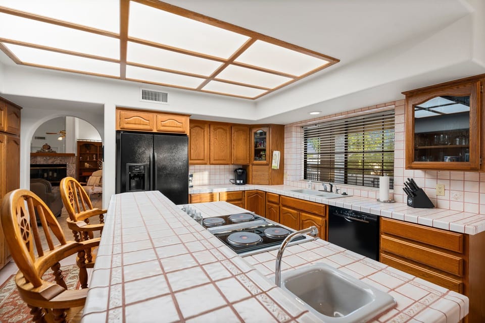 This kitchen combines elegance and functionality, featuring wooden cabinetry, black appliances, and a spacious island. Ideal for both everyday cooking and entertaining guests, it’s a space where culinary creativity can truly shine. 🍽️✨