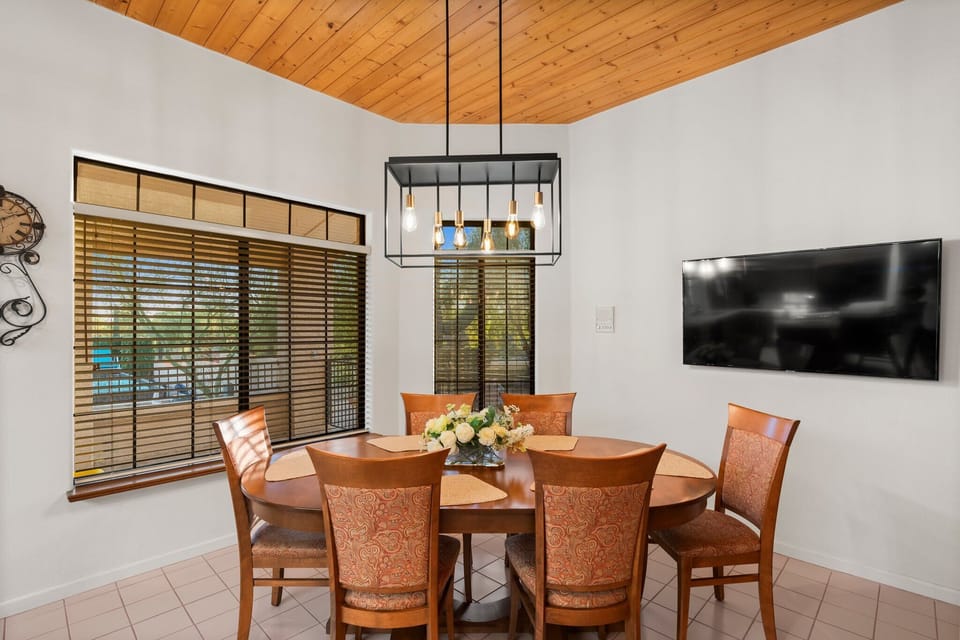 This elegant dining area, with its wooden table and modern chandelier, is perfect for hosting memorable dinners. The vaulted ceiling with exposed beams adds a touch of rustic charm, making it a cozy spot for family gatherings and celebrations.