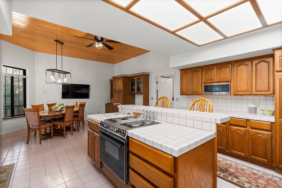 This kitchen and dining area blend rustic charm with modern elegance. With wooden cabinetry, a black countertop, and a cozy dining space, it’s perfect for family meals and entertaining guests. The vaulted ceiling and natural light create an inviting atmosphere. 🍽️✨