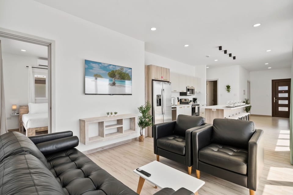 - Cozy, modern living room featuring plush leather seating and a large flat-screen TV - Cook with ease in the fully equipped, stylish kitchen with steel appliances - Seamless access to bedrooms through open-concept design for ultimate comfort