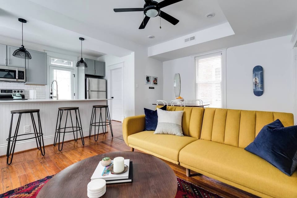 Living Room: Stylish space features a chic yellow sofa, modern kitchen island, and warm wood floors!