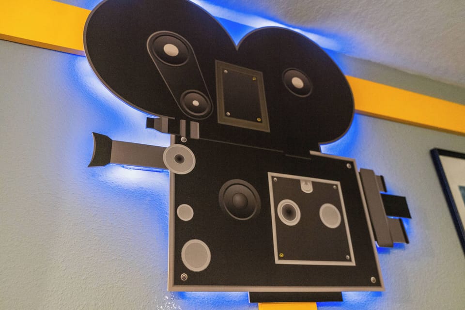 Immerse yourself in a creative space featuring a unique vintage film camera art piece bathed in soft blue light against a vibrant yellow wall, setting the mood for an inspiring and memorable stay.