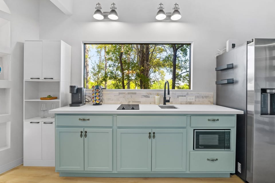 The kitchen includes a fridge, stove, microwaved, & coffee machine