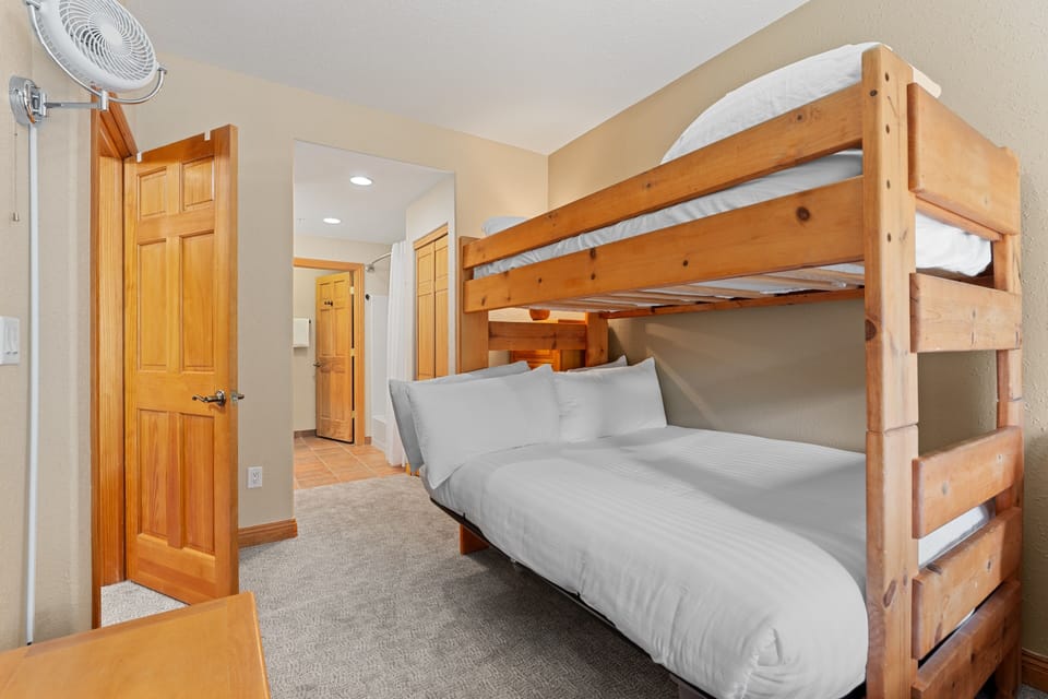 Rest easy in this cozy sleeping space, where the bunk bed maximizes room while keeping your group close. A wall-mounted fan keeps you comfortable, and the warm wood tones invite relaxation after your mountain adventures.
