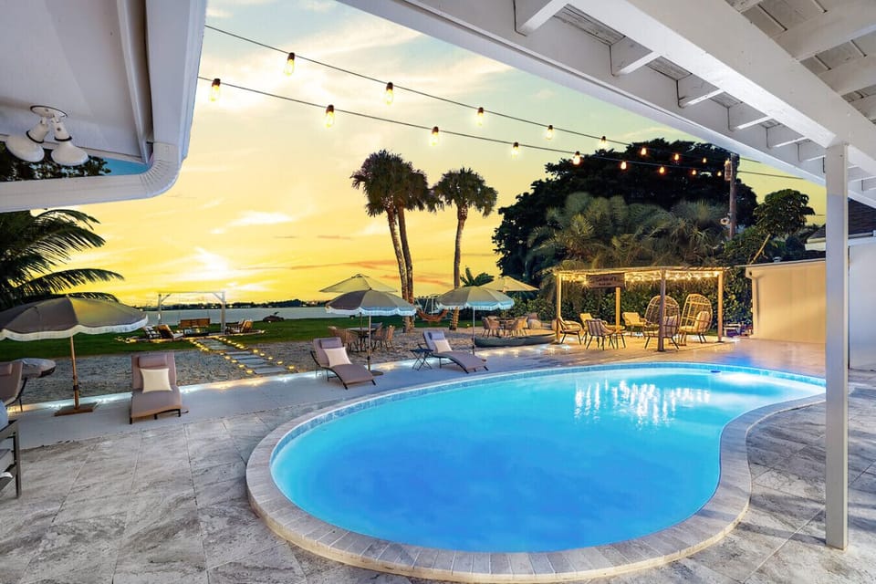 "Twilight Oasis: Enjoy Stunning Sunsets by the Curved Pool, Perfectly Complemented by Ambient Lighting and a Lush Garden Setting."
