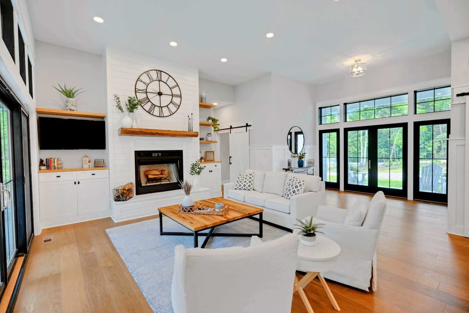 Bright and airy living room featuring a cozy fireplace, stylish furnishings, and large windows for natural light.