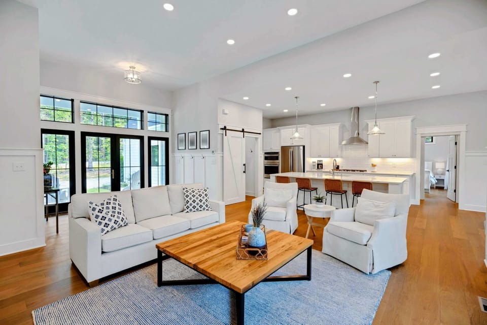 Bright and airy living room featuring a cozy fireplace, stylish furnishings, and large windows for natural light.