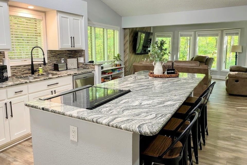Kitchen Island View into Living Area with Peaceful Wooded Views

