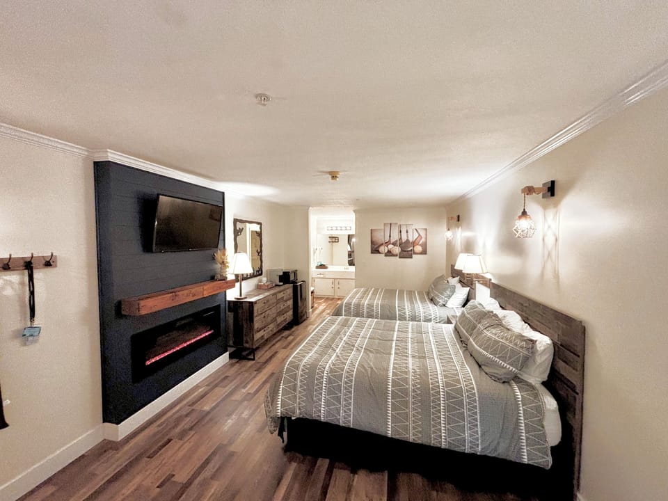 Two queen beds with TV and electric fireplace.