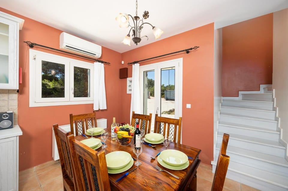 Open-plan living room with sofas, dining area, kitchen, ornamental fireplace, A/C, WiFi internet, and satellite TV