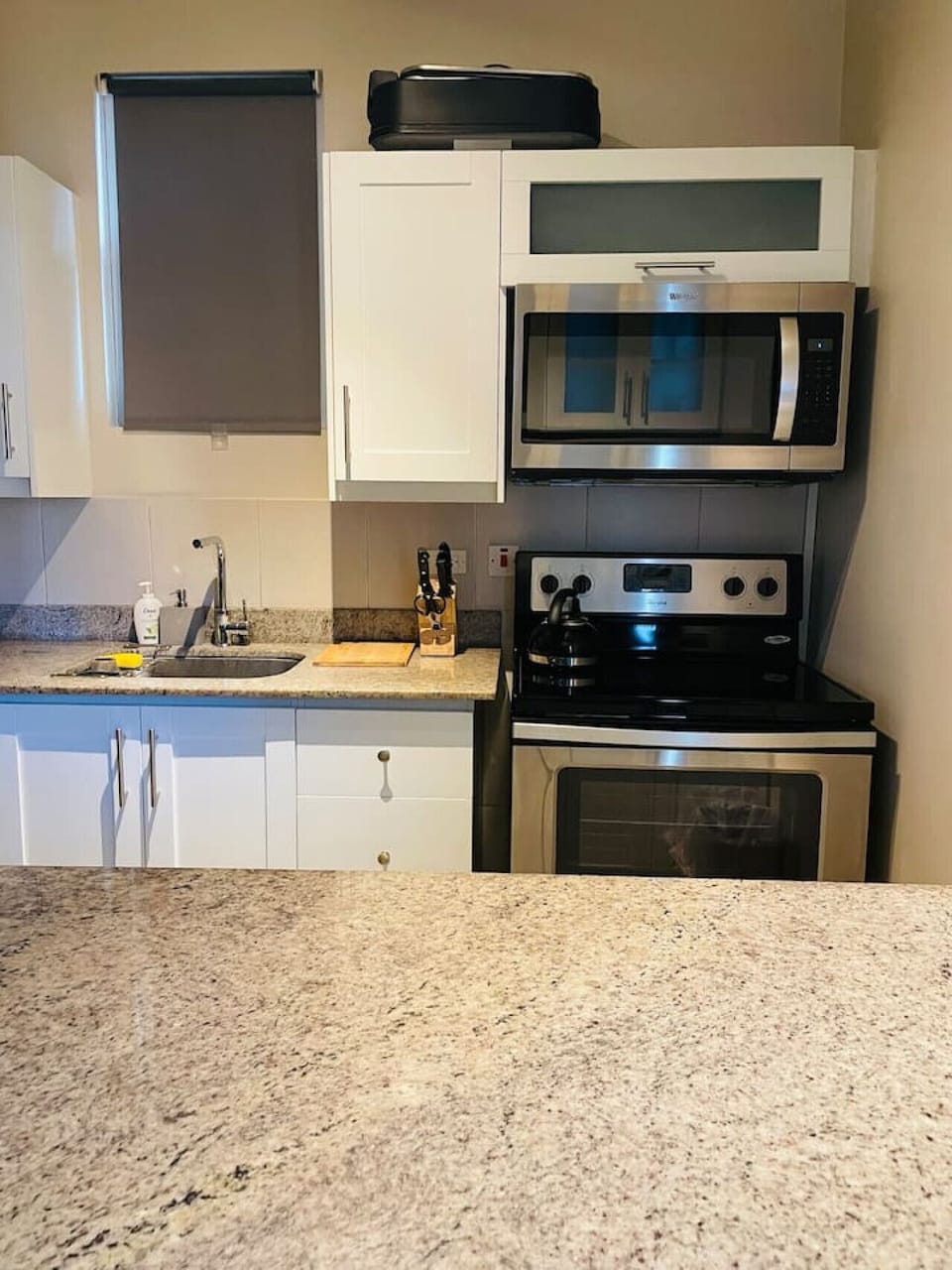Kitchen corner w/ stove, microwave, cabinets & granite countertop