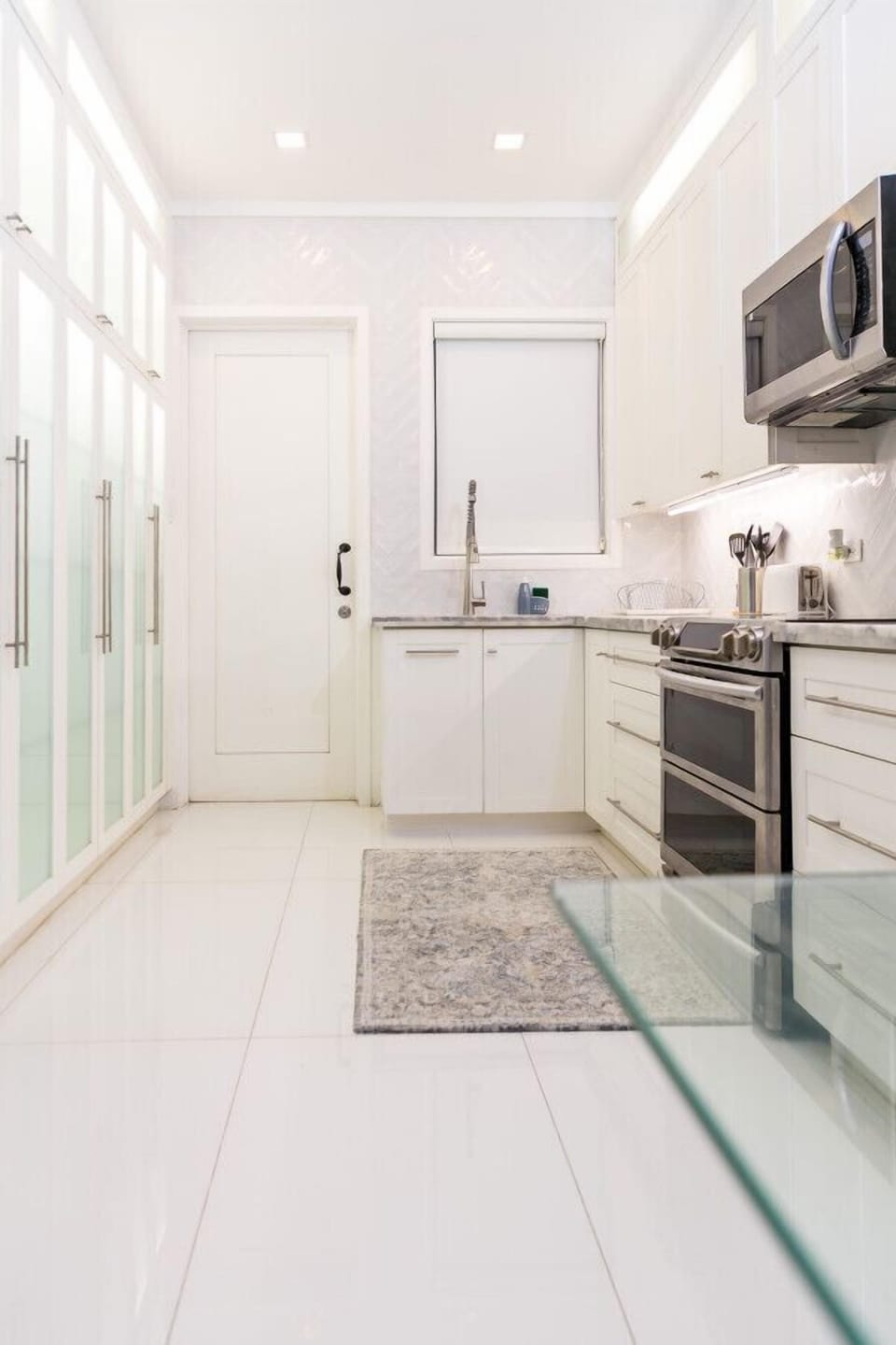 Bright kitchen w/ white cabinetry, stainless appliances & spacious counters