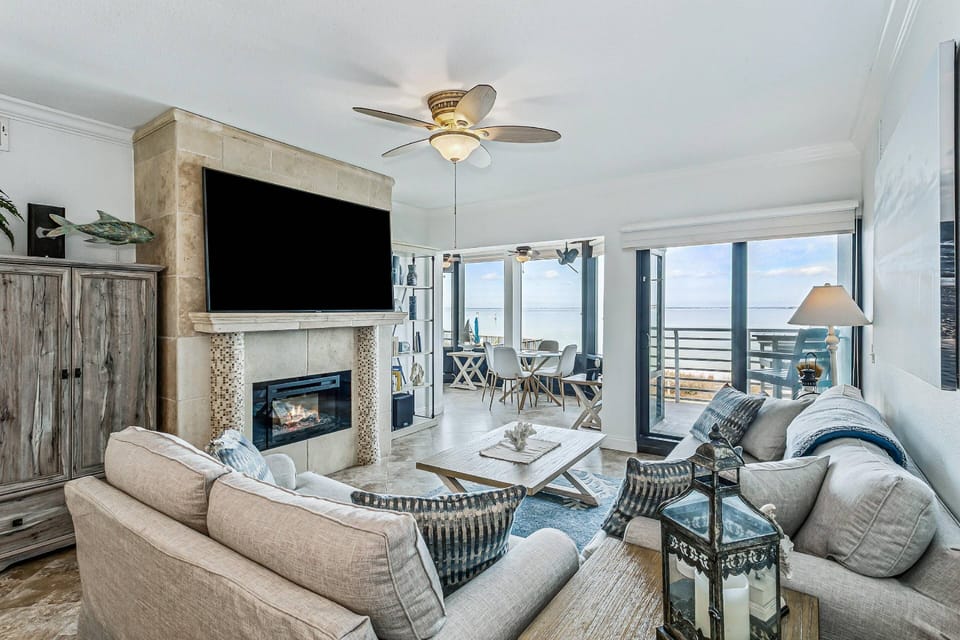 Cozy living room with huge smart TV, electric fireplace, and water views