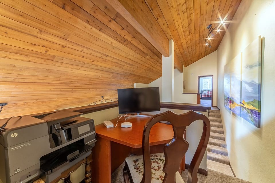 The second dedicated workspace, located on the landing at the top of the stairs, has a desk, chair, monitor and printer.