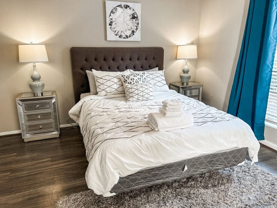The bedroom highlights a queen-size bed flanked by side tables and lamps to enjoy some reading before bed.