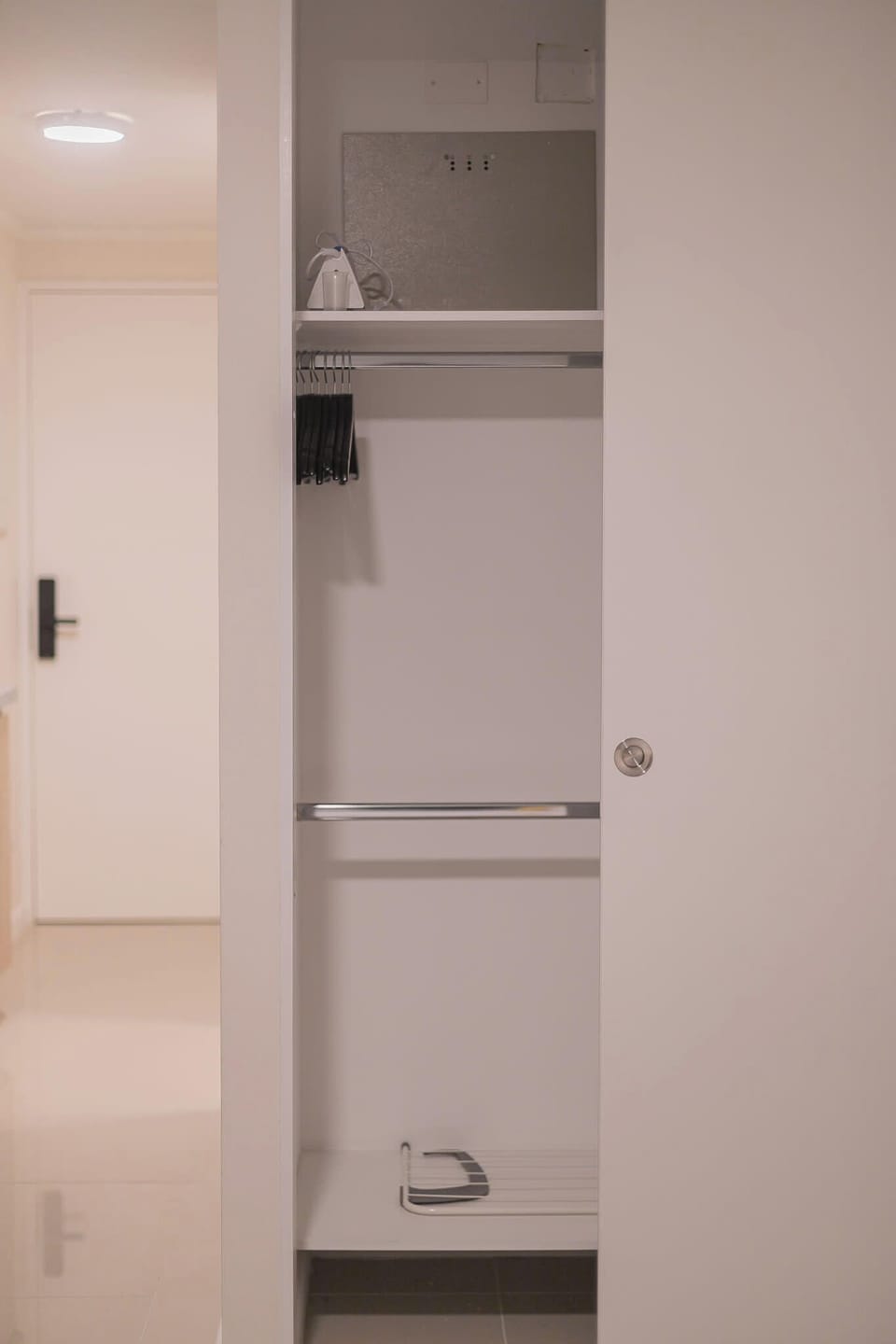 Spacious closet with hangers and ironing board for your convenience.