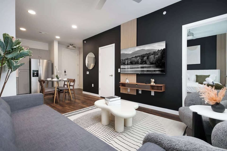 Relax in a living room filled with light, art, and comfort, featuring cozy chairs, a long sofa, and a touch of nature.