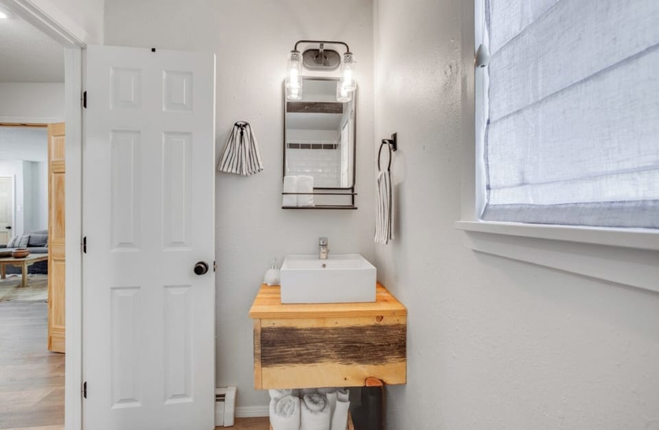 Fresh up in your stylish bathroom with a modern vessel sink, warm wood accents, and soft natural light filtering through the window.