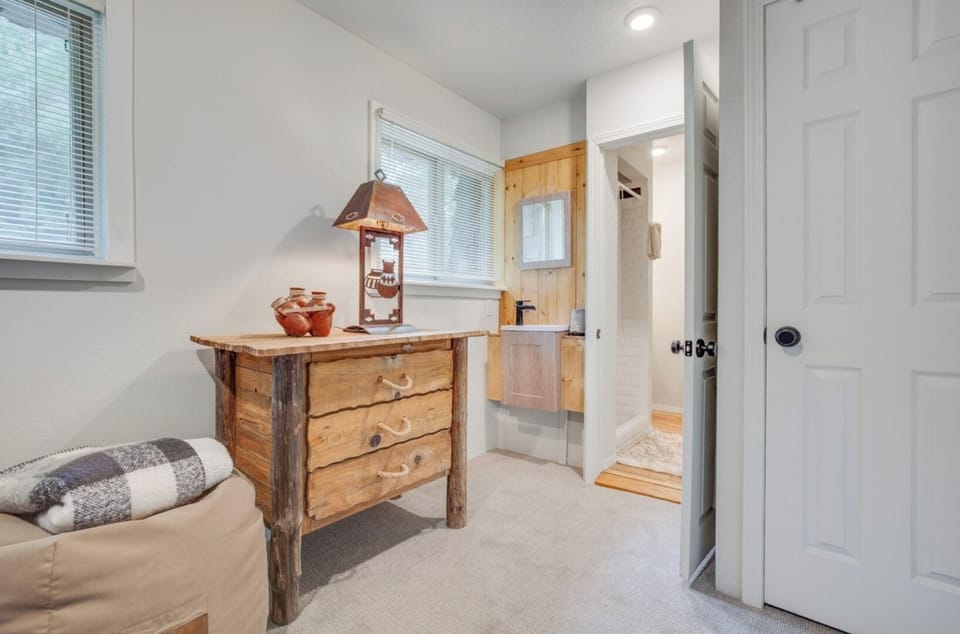 Bright, cozy room with rustic wooden dresser and natural light from multiple windows. Soft carpeting and direct access to your private en-suite bathroom for added convenience.