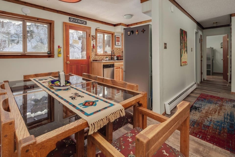Gather at this unique dining table with bench seating—natural light floods through large windows while the open kitchen invites you to prepare meals in a homey, welcoming space.