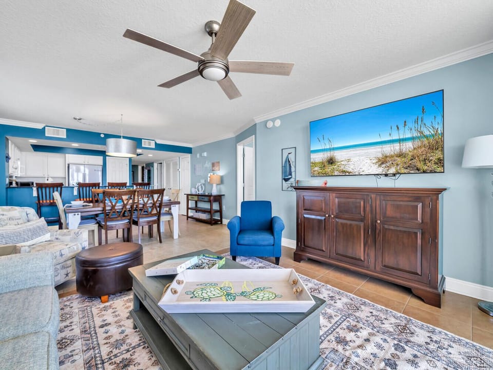 Relax in your spacious living area with coastal-inspired décor, ceiling fan comfort, and large TV for entertainment after beach days.