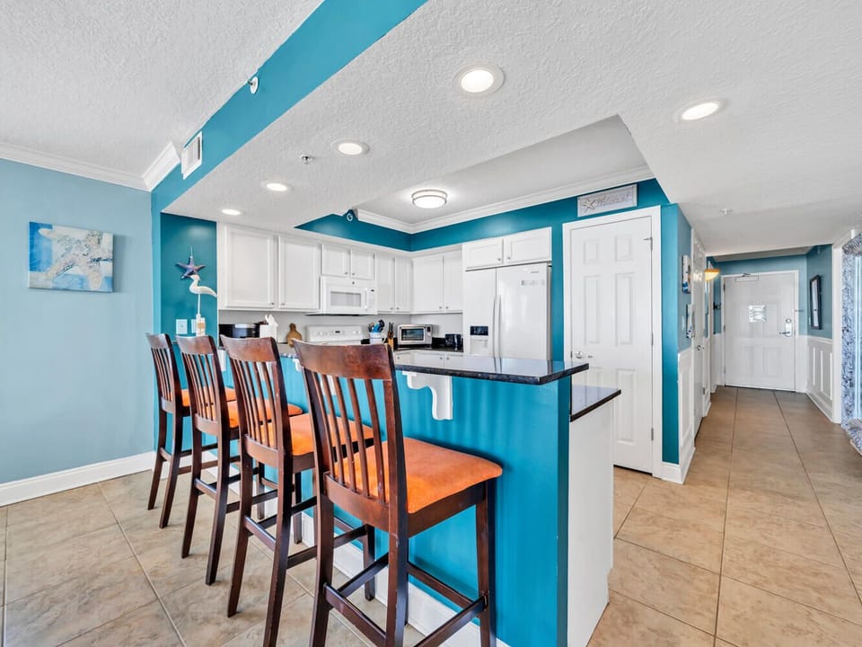 Your bright coastal kitchen awaits with ocean-inspired turquoise walls, breakfast bar seating for four, and full appliances for memorable meal prep.