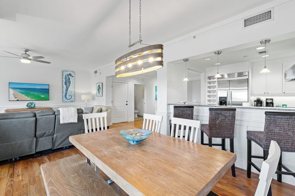 Gather around your spacious dining table where coastal artwork and warm lighting create the perfect atmosphere for memorable meals together.