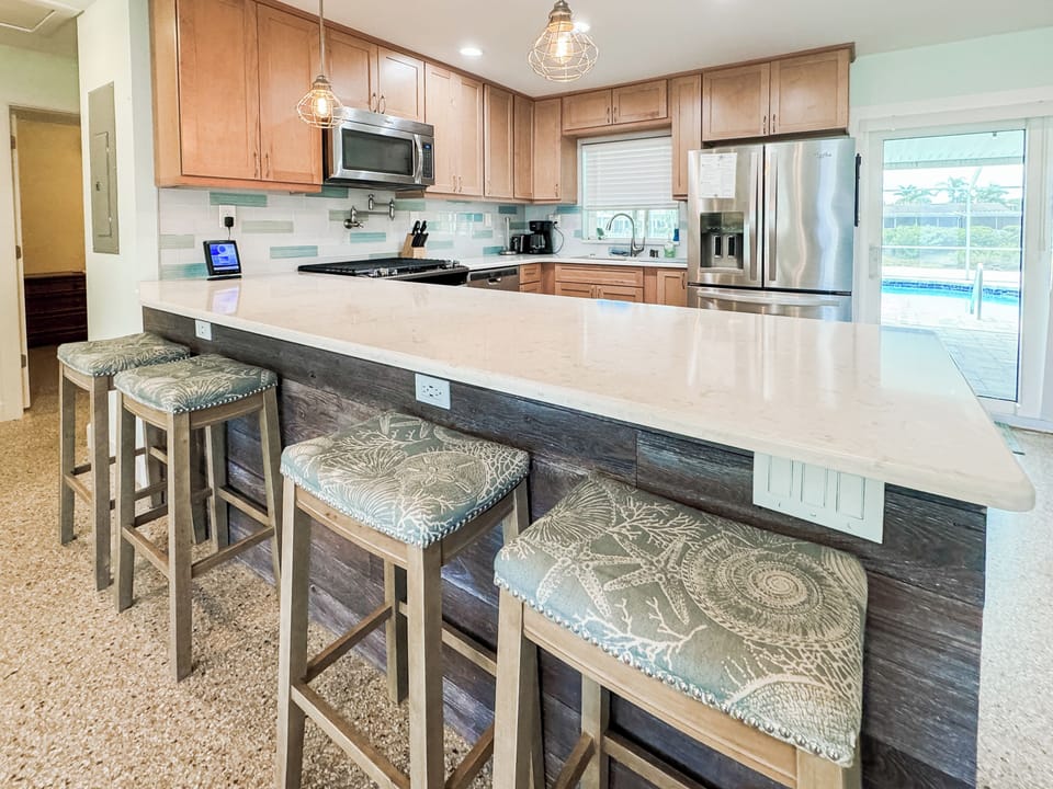 Indulge in our kitchen featuring stainless steel appliances and barstools
