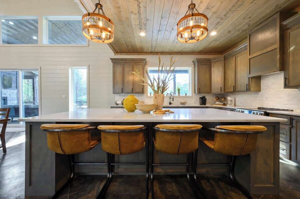 Spacious modern kitchen with island seating, pendant lights, and wood cabinetry for luxury cabin living.