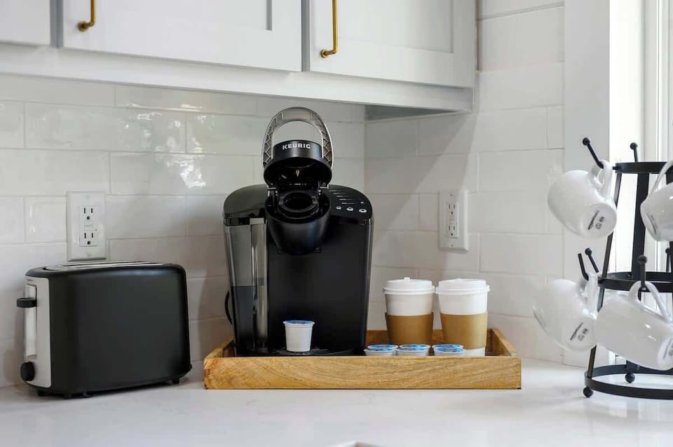 Coffee station with Keurig, to-go cups, toaster, and white mugs on display—perfect for a cozy morning in the cabin.