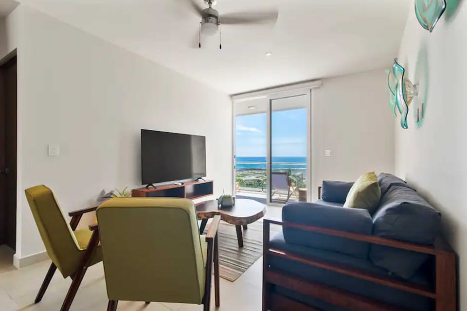 Cozy living room with sofa bed, TV, and balcony with Caribbean views.