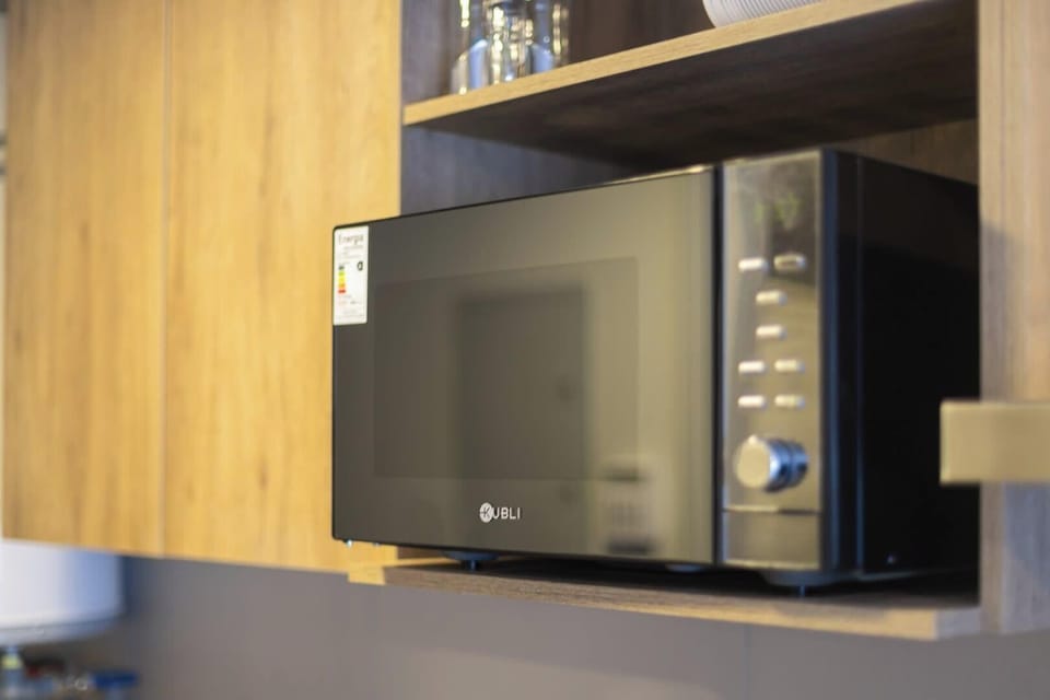 Modern kitchen convenience with sleek microwave and stylish wooden shelving.