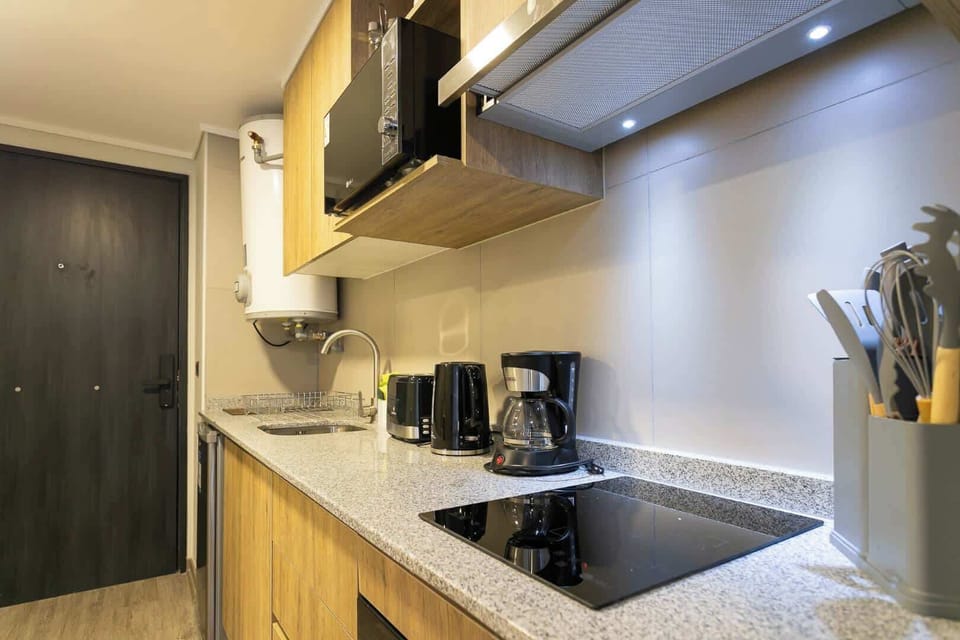 Modern and efficient kitchen with all essentials for a cozy stay, featuring sleek appliances and stylish wooden accents.