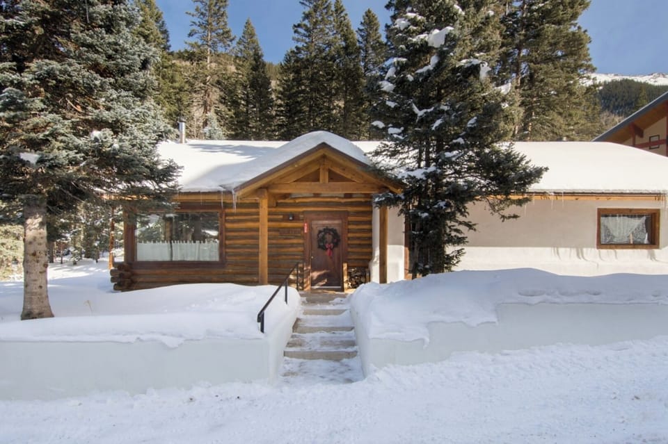A charming log cabin nestled in snowy pine forest, offering a peaceful mountain retreat with rustic elegance and natural beauty surrounding the property.