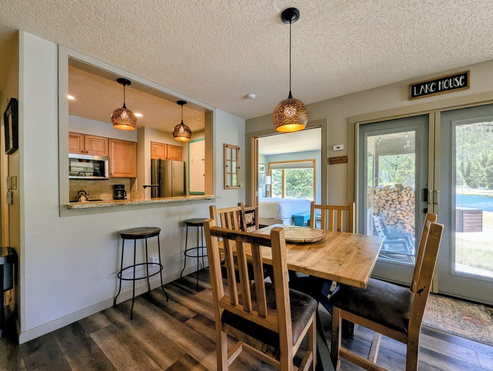Gather around this warm, inviting dining space where your group can share meals, plan adventures, and make memories. Natural light pours through sliding doors to the deck and lake beyond.