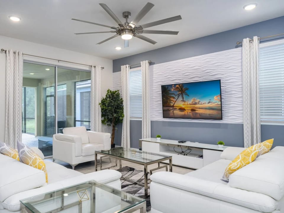 A bright living room with a large TV, comfy white sofas, and stylish decor.
