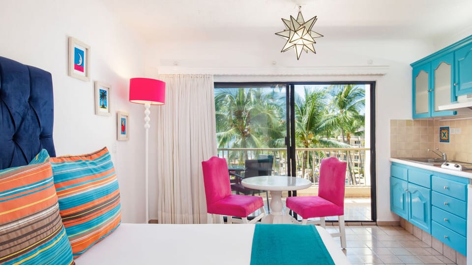 Villa del Palmar: Vibrant beachfront suite with palm views & kitchenette.