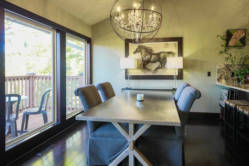 A cozy dining area with plush seating and an opulent chandelier, ideal for intimate dinners and enjoying the view through floor-to-ceiling windows.
